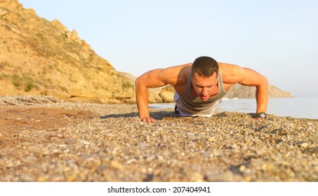 Fitness man exercising push ups.cross-training on beach with the blue sky in the background and open space around him - Powered by Shutterstock