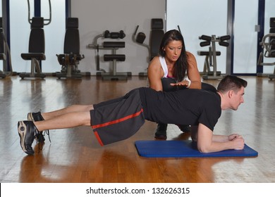 Fitness Man And Female Personal Trainer In Gym Doing Push-ups