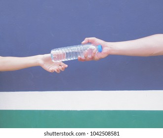 Fitness Man Giving Bottle Of Water To His Friend In The Gym.

