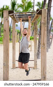 Fitness Man On Monkey Bars Fitness Station Gym. Strong Male Trainer Training On Brachiation Ladder Outdoors Equipment As Part Of Crossfit Workout Routine.