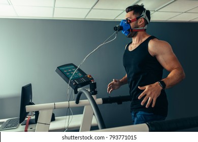 Fitness Man Running On Treadmill With A Mask Testing His Performance. Athlete Examining His Performance In Sports Science Lab.