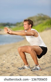 Fitness Man Training Air Squat Exercise On Beach Outside. Fit Male Exercising Crossfit Outside. Young Handsome Caucasian Male Fitness Model And Instructor Outdoors