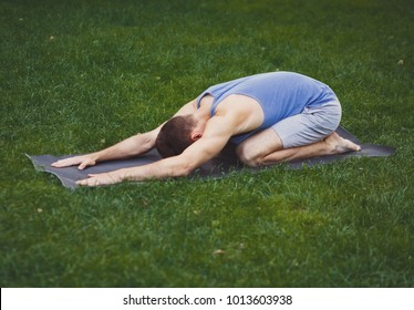 Fitness, Man Training Yoga In Child's Pose Outdoors, Copy Space. Young Sporty Guy Makes Aerobics Exercise On Grass In Park.