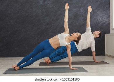 Fitness, man and woman training yoga in side plank pose at home. Young couple makes exercise, copy space - Powered by Shutterstock