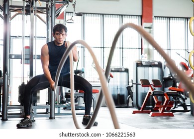 Fitness man working out with battle rope at gym - Shutterstock ID 1066221563