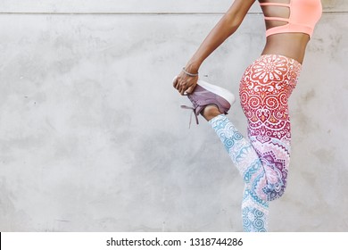 Fitness model in fashion sportswear doing yoga exercise in the city street over gray concrete background. Outdoor sports clothing and shoes, urban style.