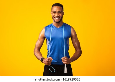 Fitness Model. Smiling afro man with jumping rope on neck isolated over yellow studio background. Copyspace - Powered by Shutterstock