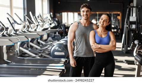 Fitness muscular couple posing in gym, strong couple standing in sports center surrounded by exercise equipment and smiling at camera - Powered by Shutterstock