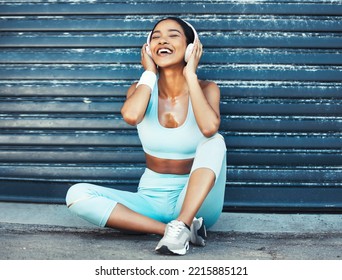 Fitness, Music And Happy Woman With Headphones Sitting On Ground For Outdoor Workout Or Running Break. Sports, Exercise And Listening To Streaming App On Earphones Enjoying Favorite Training Playlist