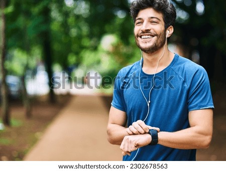 Fitness, music and man with a watch for time, running progress and heart results in a park. Smile, thinking and a male athlete listening to a podcast or audio while checking notification on a device