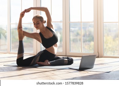 Fitness online. Athletic young woman stretching at home in the morning, using laptop, empty space - Powered by Shutterstock