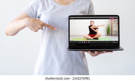 Fitness Online. Virtual Gym. Home Workout. Woman Recommending Sport Video Class Pointing At Laptop With Man Performing Stretching Exercise On Screen Isolated On Light Free Space.