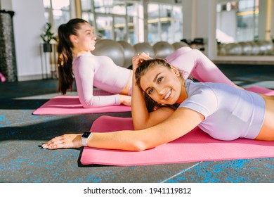 Fitness, People And Healthy Lifestyle Concept. Two Lazy Fitness Women In Yoga Class Resting On Pink Mats At Studio Or Gym.