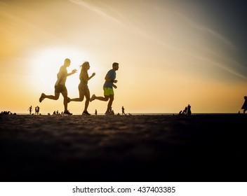 Fitness people running at the beach into the sunset. - Powered by Shutterstock