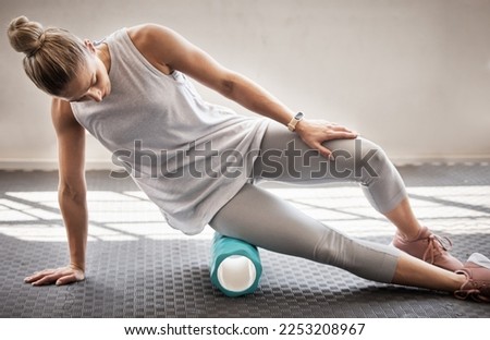 Fitness, physio massage and woman with roller on floor for leg tension and support in yoga workout at gym. Health, pilates and massaging for sports physiotherapy, girl on ground foam rolling muscle.