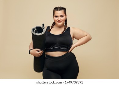 Fitness. Plus Size Model In Black Sportswear Portrait. Full-Figured Woman Holding Pilates Mat. Body Positive And Sport As Lifestyle.