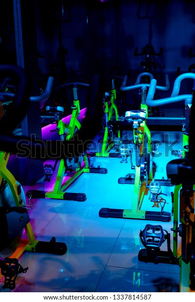 Fitness room the\
structure of the bike is interesting, whether it is a bicycle\
handlebar, a car frame, a staircase and lights in room with many\
colours of green, purple and\
blue