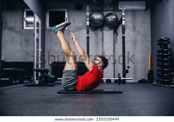 Fitness routine and weight loss, sports life. Man
correctly performs demanding core exercises on the pathos of the
modern gym and sports center concept. Individual training and
achieving fitness goals