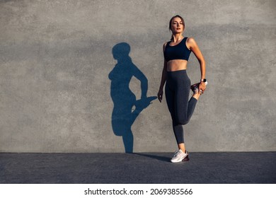 Fitness Runner Body Close Up, Woman Doing Warm-up Before Jogging, Stretching Leg Muscles, Female Athlete Prepares Legs For Cardio Workout, Outdoor Exercise On Gray Background