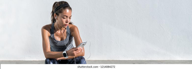 Fitness runner girl listening to music with earphones on phone wearing smartwatch. Active lifestyle woman wearable tech sports gear concept banner panorama.