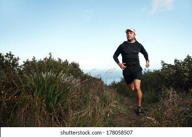 fitness running man on mountainn trail near ocean exercising for marathon training - Powered by Shutterstock