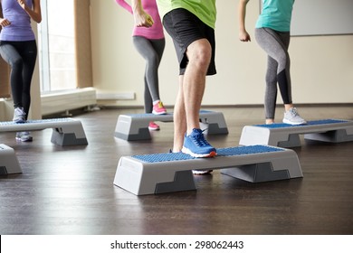 fitness, sport, aerobics and people concept - group of smiling people working out and flexing legs on step platforms in gym - Powered by Shutterstock