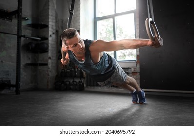 fitness, sport, bodybuilding and people concept - young man exercising on gymnastic rings in gym - Powered by Shutterstock