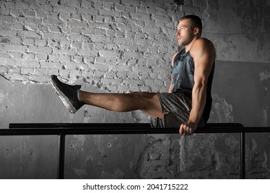 Fitness, Sport, Bodybuilding And People Concept - Young Man Doing Abdominal Exercise On Parallel Bars In Gym