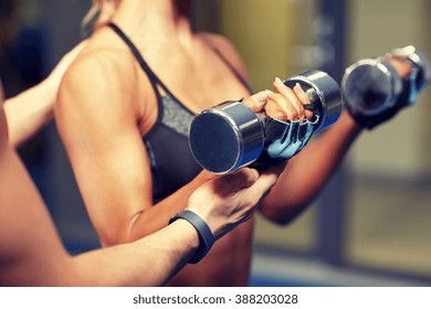 fitness, sport, bodybuilding and weightlifting concept - close up of young woman and personal trainer with dumbbells flexing muscles in gym - Powered by Shutterstock