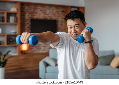 Fitness and sport concept. Active mature man exercising with two dumbbells and boxing, enjoying domestic morning workout, free copy space - Powered by Shutterstock