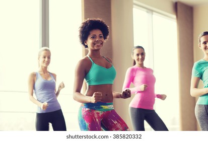fitness, sport, dance and lifestyle concept - group of smiling people with coach dancing zumba in gym or studio