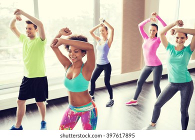 Fitness, Sport, Dance And Lifestyle Concept - Group Of Smiling People With Coach Dancing In Gym Or Studio