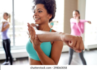fitness, sport, dance, people  and lifestyle concept - close up of smiling african american woman with group of women dancing zumba in gym or studio