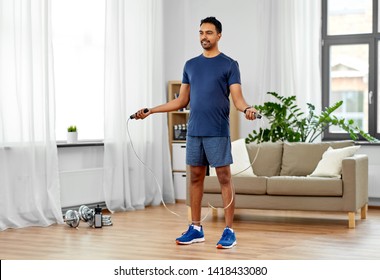 fitness, sport, exercising and healthy lifestyle concept - indian man skipping with jump rope at home - Powered by Shutterstock