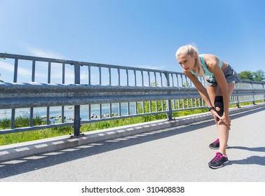 Fitness, Sport, Exercising And Healthy Lifestyle Concept - Young Woman With Knee Support Brace Injured Leg Outdoors