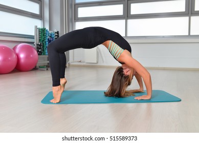 Fitness, sport, exercising lifestyle - female Model with long hair doing Yoga Bridge Pose at gym, Upward Bow or Wheel Posture - Powered by Shutterstock