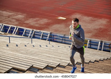 fitness, sport, exercising and people concept - young man running upstairs on stadium - Powered by Shutterstock