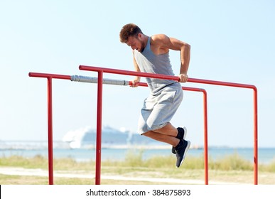 fitness, sport, exercising, training and lifestyle concept - young man doing triceps dip on parallel bars outdoors