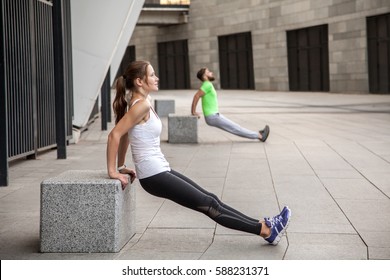 Fitness, Sport, Exercising, Training And People Concept - Couple Doing Triceps Dip Exercise On City Street Bench
