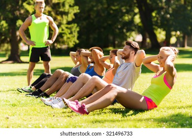 fitness, sport, friendship and healthy lifestyle concept - group of happy teenage friends or sportsmen exercising and doing sit-ups at boot camp - Powered by Shutterstock