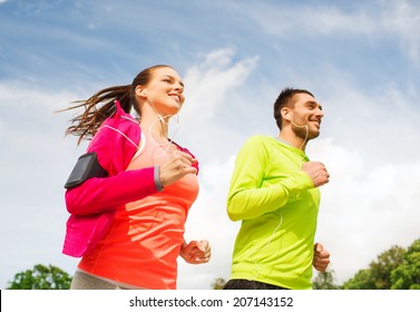 fitness, sport, friendship and lifestyle concept - smiling couple with earphones running outdoors - Powered by Shutterstock