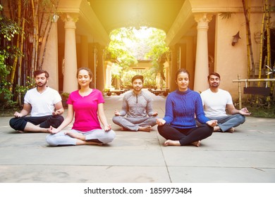 fitness, sport and healthy lifestyle concept - group of Indian asian young people doing yoga poses or meditation outdoors - Powered by Shutterstock