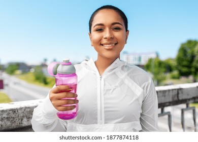 fitness, sport and healthy lifestyle concept - happy smiling young african american woman drinking water from bottle outdoors - Powered by Shutterstock