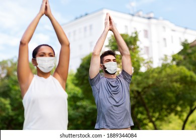 fitness, sport and healthy lifestyle concept - group of happy people wearing face protective medical mask for protection from virus disease doing yoga at summer park - Powered by Shutterstock