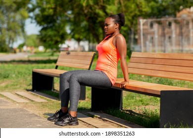 fitness, sport and healthy lifestyle concept - young african american woman doing bench triceps dip outdoors