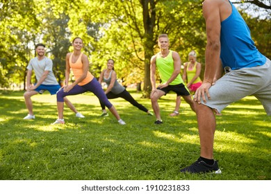 fitness, sport and healthy lifestyle concept - group of happy people exercising with trainer at summer park - Powered by Shutterstock