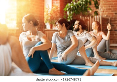 fitness, sport and healthy lifestyle concept - group of people doing yoga seated spinal twist pose in gym or studio