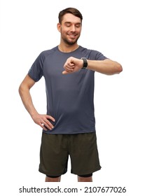 Fitness, Sport And Healthy Lifestyle Concept - Smiling Man In Sports Clothes Looking At His Smart Watch Or Tracker Over White Background