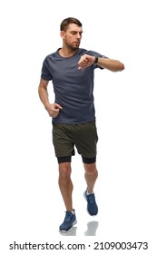 Fitness, Sport And Healthy Lifestyle Concept - Man In Sports Clothes Looking At His Smart Watch Or Tracker Running Over White Background