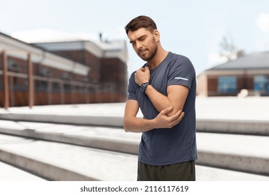 Fitness, Sport And Healthy Lifestyle Concept - Man With Smart Watch Or Tracker Holding To Injured Hand Over City Street Background